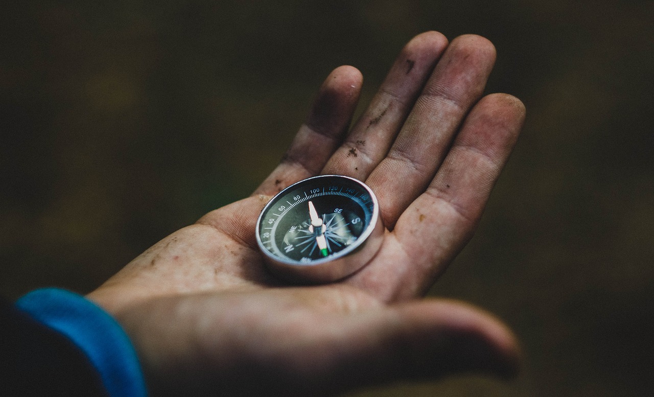 A dirty hand holding a compass, representing the guidance needed for good psilocybin treatment results.