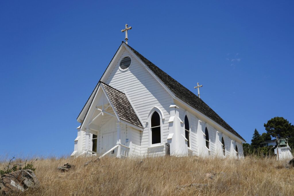 White country church under a clear blue sky, representing the intersection of faith and psilocybin experiences. Recent studies show clergy reporting mystical states and spiritual healing through legal psychedelics in Oregon. Vital Reset supports safe psilocybin treatment, psilocybin retreats, and magic mushroom therapy for personal and spiritual growth.