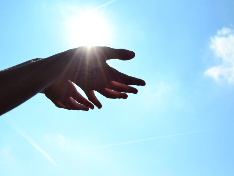 Outstretched hands reaching toward the sun, symbolizing spiritual connection and psilocybin experiences in Oregon.