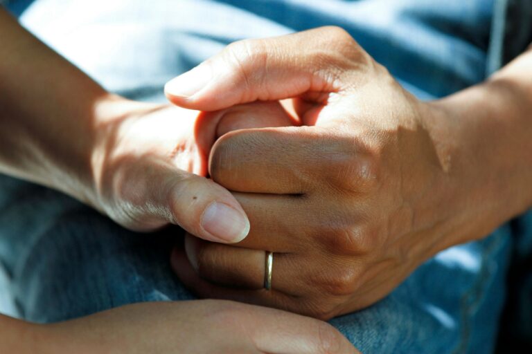 "Safe psilocybin treatment in Oregon, close-up of supportive hand-holding during a medical evaluation at a psilocybin service center"